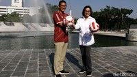 Sri Mulyani dan Sandiaga Uno berpose di depan air mancur di sekitar Monumen Pembebasan Irian Barat. Mereka kompak memegang bola.