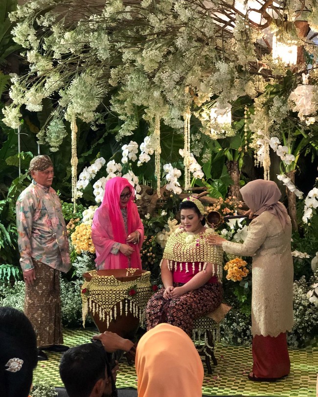 Rangkaian proses pernikahan anak Tutut Soeharto dan Indra Rukmana dimulai dari siraman. Prosesi siraman digelar di rumah Tutut di kawasan Menteng Jakarta Pusat, Sabtu (5/5/2018). Area taman rumah disulap menjadi tampak mewah dan elegan dengan hiasan bunga berwarna putih. Istri Wapres JK, Mufidah Kalla menjadi salah satu pihak yang ikut dalam prosesi siraman tersebut. Foto: Instagram/robbyray_yohannesbridal