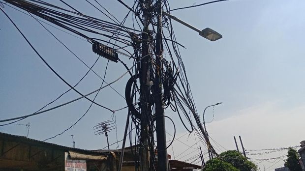 Gulungan kabel-kabel tidak teratur menempel di tiang listrik