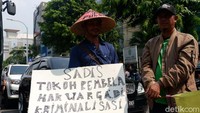 Massa membawa karton dan spanduk yang berisi tulisan protes terkait penerbitan sertifikat.