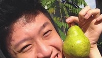 Nggak kalah manis, ini senyum Rich Brian saat memegang sebuah pir hijau. Ada-ada saja ya? Foto: Instagram brianimanuel