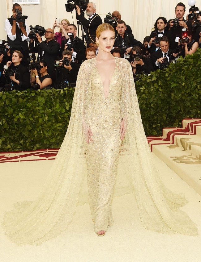 Rosie Huntington-Whiteley memikat bagai malaikat berbalut gaun emas dengan aksen cape dari Ralph Lauren. Foto: Getty Images