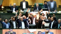 Dalam foto-foto yang dipublikasi di berbagai media Iran seperti dilansir kantor berita AFP, Rabu (9/5/2018), tampak seorang anggota parlemen mengacungkan bendera kertas Amerka dan membakarnya di tengah-tengah ruang parlemen. (Foto: Dok. AFP via The Sun)