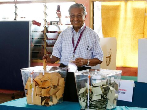 Mahathir tersenyum saat memasukkan surat suara ke kotak suara usai memilih