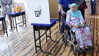 PM Najib membantu ibunya, Rahah Noah yang berkursi roda untuk menggunakan hak suaranya di tempat pemungutan suara (TPS) di Pekan hari ini. (Foto: Reuters)