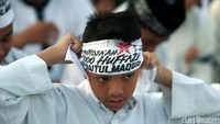 Menggunakan baju putih, seorang anak menggunakan ikat kepala membela Palestina.