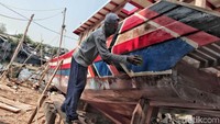 Seorang pekerja sedang menghias/mengecat badan kapal agar semakin menarik untuk dilihat.