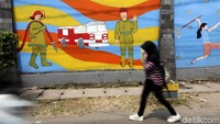 Seorang warga melintas diantara tembok-tembok yang sudah dpercantik dengan seni mural.