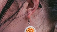 Anting yang dikenakan oleh Emma pun bentuknya sangat unik. Lagi-lagi mac and cheese dengan paduan keju dan saus sambal. Foto: Christina Riley / SWNS