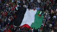 Massa membentangkan bendera Palestina berukuran raksasa. REUTERS/Osman Orsal.