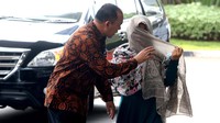 Seorang perempuan itu sempat menutupi wajahnya dengan kerudung.