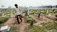 Petugas lainnya melakukan perawatan makam.