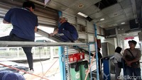 Sambil menunggu bus datang, seorang penumpang melihat proses perbaikan halte.