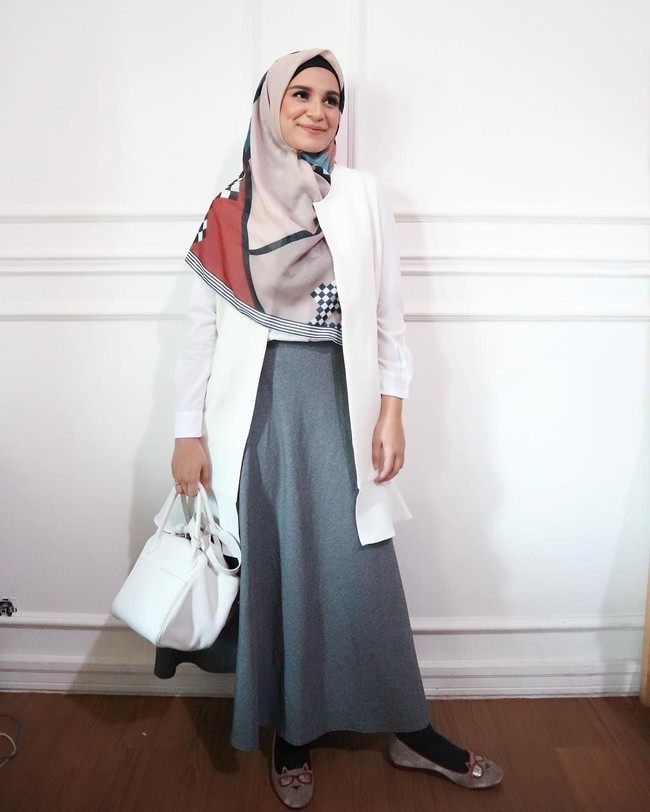 Shireen Sungkar juga tampil kasual dengan outerwear panjang berwarna putih. Ia padukan atasannya dengan rok bersiluet A dan hijab motif yang dipakai menutupi dada. Foto: Instagram/ShireenSungkar