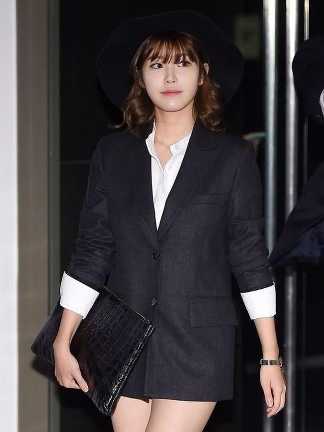 Gaya preppy ditunjukkan Hyosung yang memakai jas oversized dan kemeja putih, lengkap dengan topi dan clutch. Tak terlihat juga celana yang dipakainya. Foto: Koreaboo
