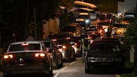 Mobil-mobil polisi memasuki jalan menuju kediaman Najib di Kuala Lumpur pada Rabu (16/5) untuk melakukan penggeledahan yang disebut terkait penyelidikan skandal mega korupsi 1MDB. (Foto: AFP)