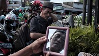 Seorang pembeli sedang menajajal peci yang akan dibelinya.