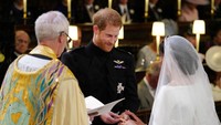 Pangeran Harry tampak memakaikan cincin di jemari Meghan Markle. Jonathan Brady/Pool via REUTERS