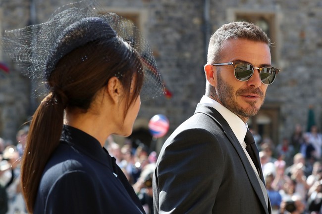 Sang suami pun tak kalah modis. David Beckham memilih tampilan formal dengan morning suit berjas klasik panjang. Tidak ketinggalan, kacamata hitam yang memberi nuansa kekinian. Foto: Getty Images