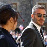 Sang suami pun tak kalah modis. David Beckham memilih tampilan formal dengan morning suit berjas klasik panjang. Tidak ketinggalan, kacamata hitam yang memberi nuansa kekinian. Foto: Getty Images