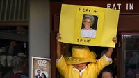 Ada seorang wanita yang memakai baju kuning menunjukkan tulisan Here In Spirit. Ia pun seorang penggemar Pangeran Harry dan Meghan Markle. Foto: Leon Neal/Getty Images