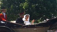 Meghan tampak anggun duduk di kereta kuda di samping Pangeran Harry. Dia melambaikan tangan ke arah fans.