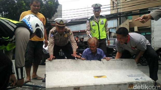 Polisi dan warga mengembalikan posisi beton di Jl Mampang Prapatan.