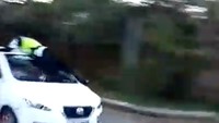 Dari video yang beredar, Minggu (20/5/2018), polantas yang menggunakan atribut lengkap ini bergelantungan di atas sebuah mobil bercat putih.  (Foto: Dok. Screenshot video yang beredar)