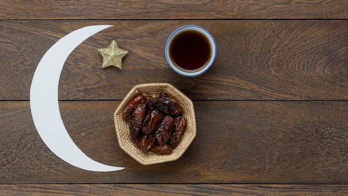 Single cup of dates juice, a sugarless healthy drink, and some dried dates placed in wooden fiber tablecloth