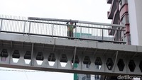 Seorang pekerja sedang menyusun besi pegangan jembatan.