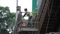 Seorang pekerja sedang membawa material bangunan.