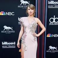Untuk momen istimewa tersebut, Taylor Swift mengandalkan gaun Versace berwarna dusty-pink yang dihiasi detail bulu-bulan di bagian dada. (Foto: Frazer Harrison/Getty Images)