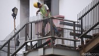 Terlihat seorang pekerja sedang melakukan las di pagar tangga jembatan.