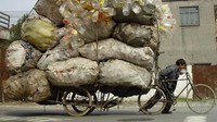Seorang pemulung menarik becaknya yang membawa tumpukan plastik bekas di Shanghai.