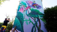 Seorang warga sedang memotret mural hasil karya seniman Natalia Rak di Festival Mural Berlin 2018. Fabrizio Bensch/Reuters.