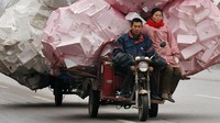 Seorang pria dan wanita mengendarai becak yang membawa tumpukan stereofoam di Shouguang.