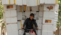 Seorang wanita membawa tumpukan kotak karet sintesis dengan becak kecilnya di Shanghai.