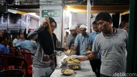 Panitia masjid melayani jamaah yang akan makan malam.