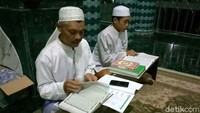 Para jamaah duduk di lantai sekitar Alquran besar untuk menyimak. Sedangkan pembaca utama duduk di kursi atau berdiri, tepat di depan Al qran raksasa itu. Ardian Fanani/detikcom.