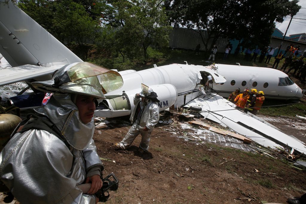 Firefighters stand near a Gulfstream G200 aircraft that skidded off the runway during landing at Toncontin International Airport in Tegucigalpa, Honduras May 22, 2018. REUTERS/Jorge Cabrera