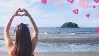Main di pantai, Maria Ozawa mengenakan bikini hitam sambil berpose love dengan tangan di udara. Makin gemas deh sama Maria Ozawa. (maria.ozawa/Instagram)