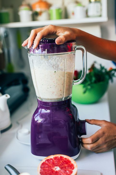 Woman making a healthy smoothie on a blender.