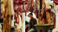 Seorang pedagang sedang memisahkan daging dengan tulang sapi.