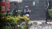 Polisi bersenjata lengkap mencari sumber ledakan.