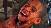 Reaksi seorang anak ketika mendapat semprotan air dingin di wajah. (Foto: Reuters)