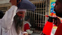 Di jalanan semprotan air diberikan agar orang-orang tidak terserang heat stroke. Kondisi di mana tubuh terlalu panas hingga mengalami kegagalan fungsi organ. (Foto: Reuters)