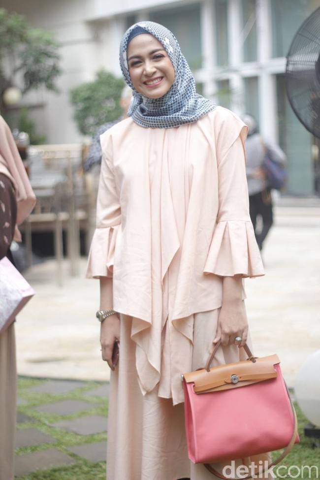 Nina Zatulani memakai warna senada dengan Nycta Gina. Ia memilih tunik dengan aksen layering di bagian depan dan lengan lonceng. Ia padukan tunik tersebut dengan hijab segi empat motif bercorak geometris yang merupakan bagian dari koleksi terbaru Pelangi Asmara. Foto: Silmia Putri/Wolipop