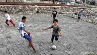Sejumlah anak bermain bola di pinggir rel kereta api, Kampung Bahari, Jakarta Utara. 