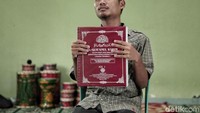 Seorang santri berfoto dengan memegang Alquran braille.