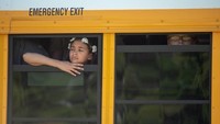 Para siswa menatap cemas dari dalam bus, menanti dijemput orang tua mereka. Foto: Kevin Moloney/AFP